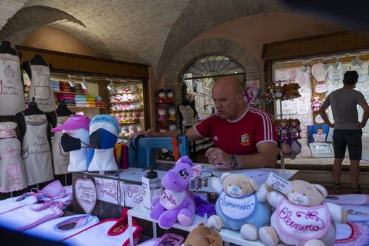 assisi,italy july 11 2020:man embroidering decorations on fabric with machinery