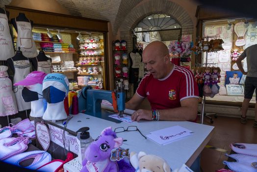 assisi,italy july 11 2020:man embroidering decorations on fabric with machinery