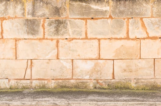 Grunge old stone wall texture background with sidewalk