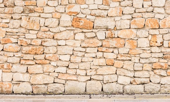 Rustic old stone wall background texture with sidewalk