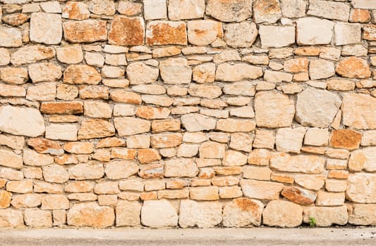 Old stone wall texture background with sidewalk