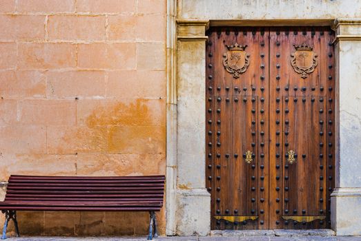 Detail view of an old elegant wooden gate and bench in front of wall background
