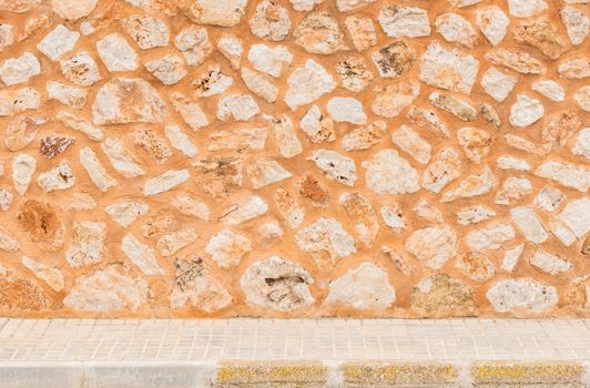 Old stone wall texture background with sidewalk