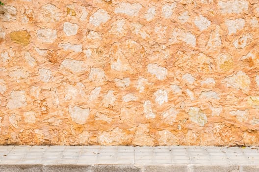 Rustic old stone wall background texture with pavement