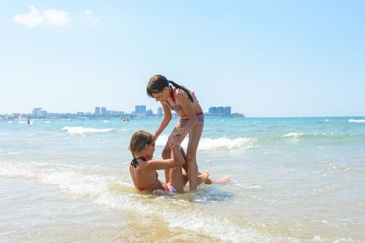 Two girls wallow each other in shallow sea