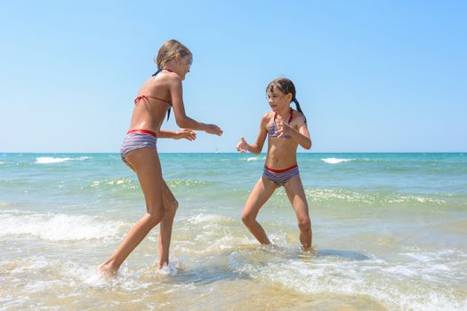 Two girls playing fight on the seashore in the water