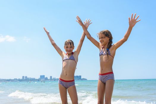 Two girls joyfully raised their hands up on the sea on vacation and swimming