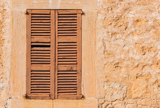 Brown wooden mediterranean window shutters and wall background 
