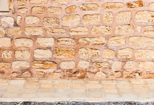 Rustic old stone wall texture background with pavement