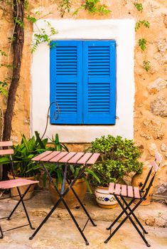 Idyllic terrace place with chairs and table and mediterranean blue window shutter background