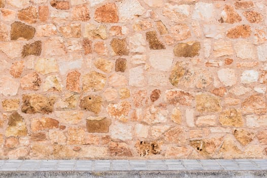 Rustic stone wall background texture with sidewalk