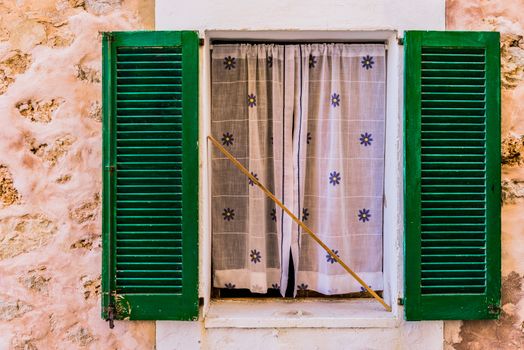 Old mediterranean green window shutters and wall background 