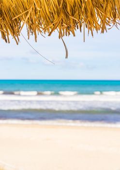 Sandy beach summer holiday background concept with straw sunshade umbrella