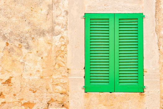 Detail view of green wooden window shutters and rustic old wall background