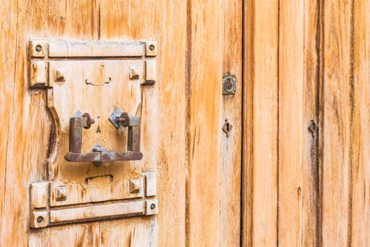 Close-up of old wooden front door with door knocker and keywhole