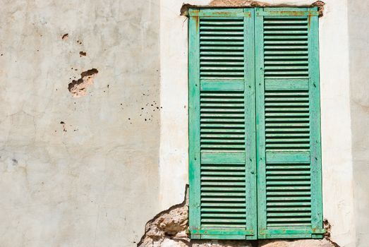 Detail view of old wooden green window shutters and grunge damaged wall