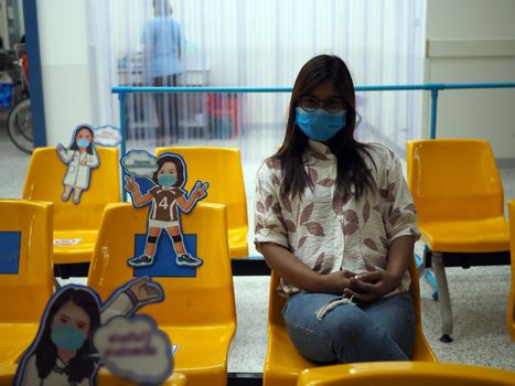 Asian women wear protective masks and sit on chairs to maintain the social distance prepared by the hospital. Social distance concept. new normal concept.
