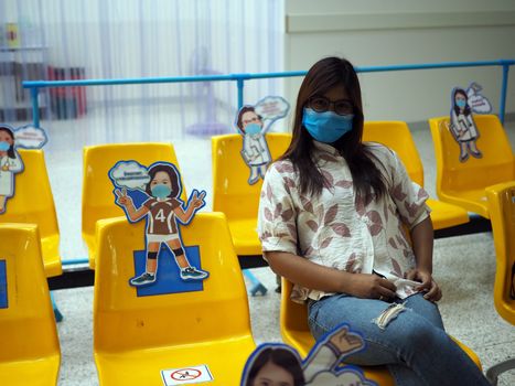 Asian women wear protective masks and sit on chairs to maintain the social distance prepared by the hospital. Social distance concept. new normal concept.