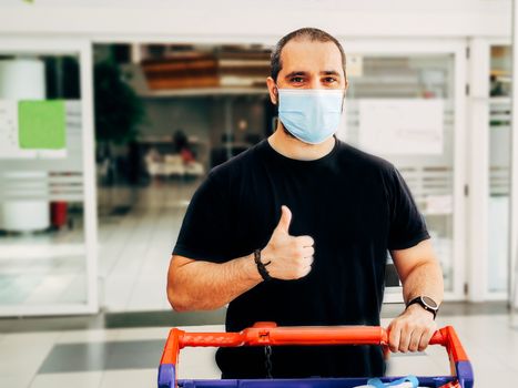 man in medical mask shopping at supermarket with thumb up.