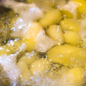 Cooking Potatoes In Boiling Water - Potatoes are being cooked in boiling water in a cooking pot. Extreme close-up.