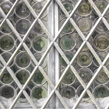 Window with white grate on background of matt glass with pattern of circles. Retro style and faded tones.