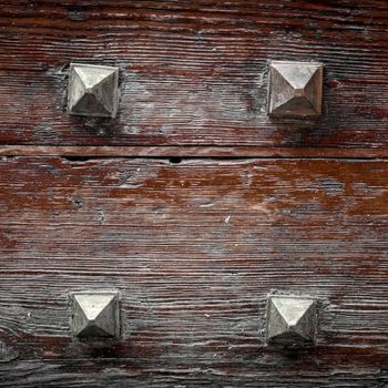 Extreme close-up of woden door of a castle with four iron nails.