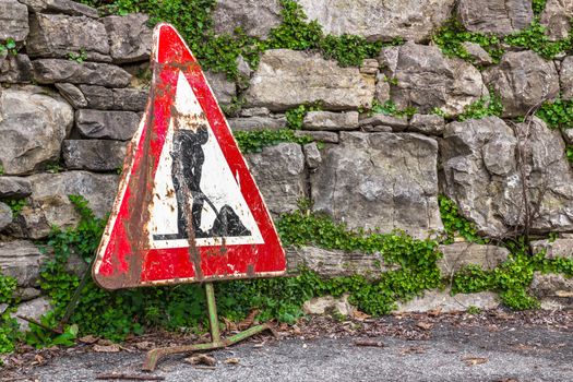 Old work in progress road sign with brick wall on background.