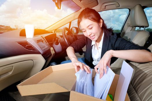 Young working woman drinking coffee and reading documents in the car before going to work