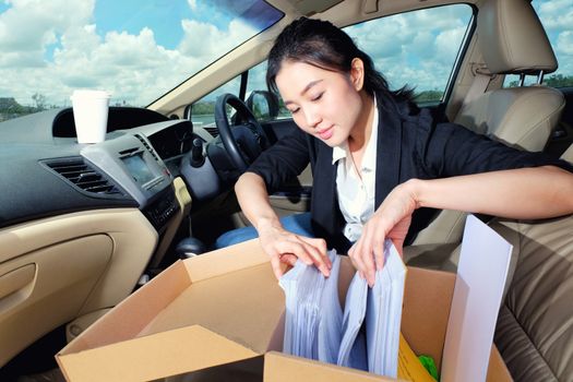 Young working woman drinking coffee and reading documents in the car before going to work