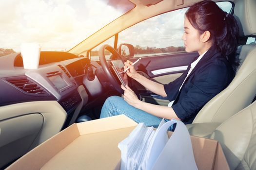 Young working woman using digital tablet in the car