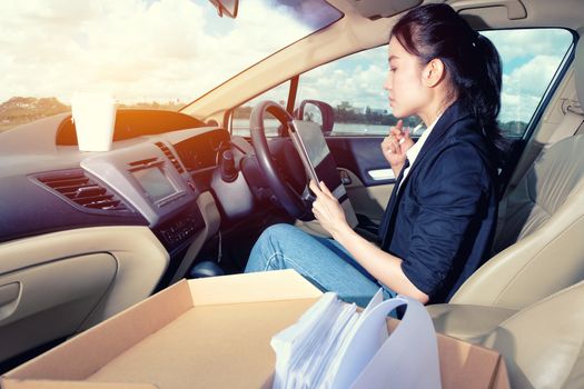 Young working woman using digital tablet in the car