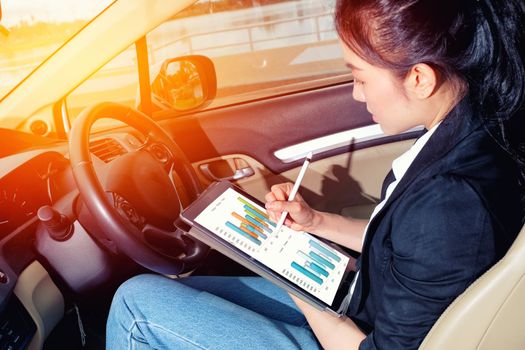 Young working woman using digital tablet in the car