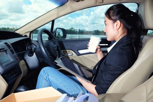 Young working woman using digital tablet in the car