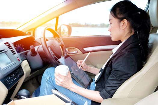 Young working woman using digital tablet in the car

