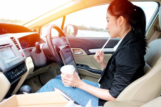 Young working woman using digital tablet in the car