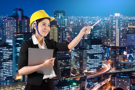 Young woman engineer holding digital tablet wtih smile in night cityscape background