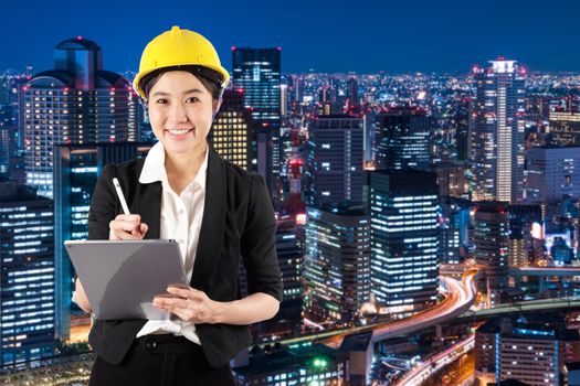 Young woman engineer holding digital tablet wtih smile in night cityscape background