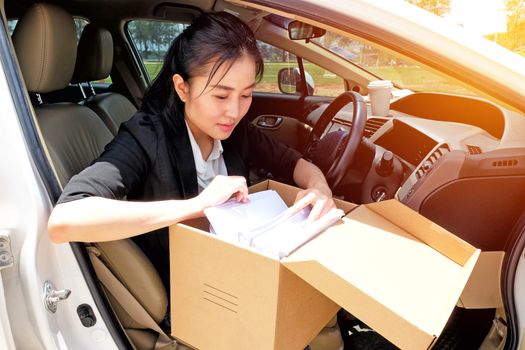 Young working woman drinking coffee and reading documents in the car before going to work