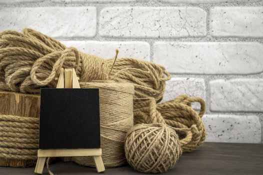 Assorted balls of hemp twine and string with skeins of rope and slate chalkboard in a close up rustic still life