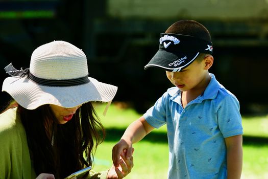 An unidentified young asian woman talking to her little son