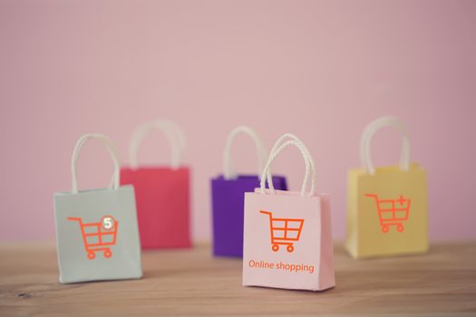 Shopping Online and e-commerce concept: Paper shopping bags with shopping cart icon on table. Online stores are considered as another medium of trading goods between entrepreneurs and customers.