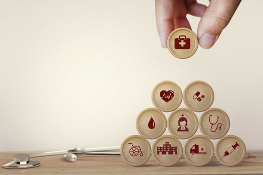 Healthcare concept about of health and medical insurance, Hand arranging block sphere stacking with icon health care medical on table wooden background.