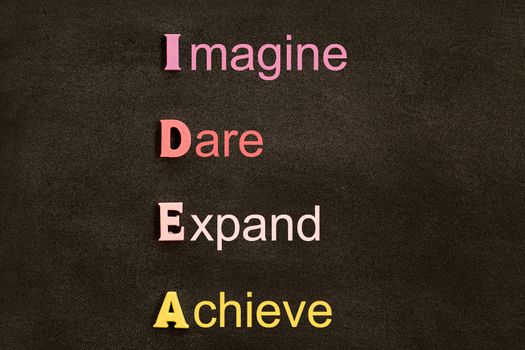 Creative idea acronym, business concept: By arrangement wooden letters (Imagine, Dare, Expand, Achieve) on black chalkboard