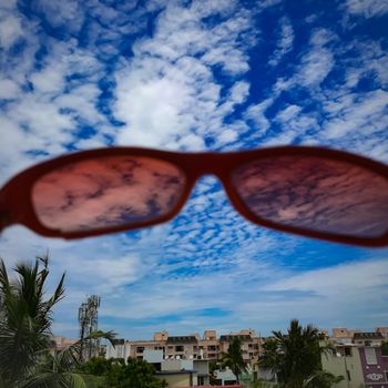 Chennai, India - July 3 2020: Red color glass placed in wall to see beautiful view of the sky from the glass lens and foreground view of buildings