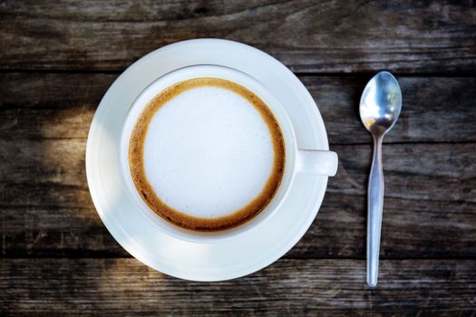 Coffee cup and spoon on wooden table with background.