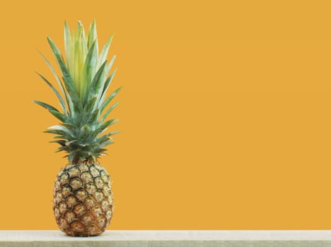 Pineapple on wood with yellow background.