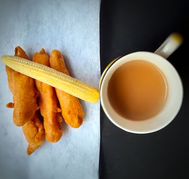 Delicious hot Baby corn baji with fresh baby corn and cup of tea placed in plate with white and black backgrounds and packed with vital antioxidants and has essential fibres
