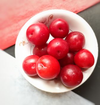 Colorful Red plums kept in bowl placed in colors backgrounds and reduce the risk of cancer heart disease and diabetes