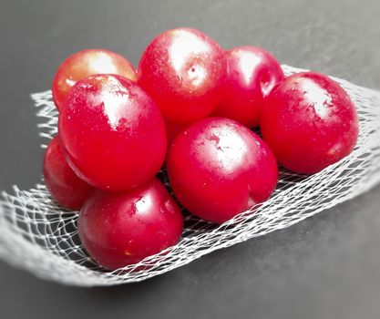 Colorful Red plums kept in fruit cover placed in black background and reduce the risk of cancer heart disease and diabetes