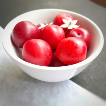 Colorful Red plums kept in bowl placed in white and black background and reduce the risk of cancer heart disease and diabetes